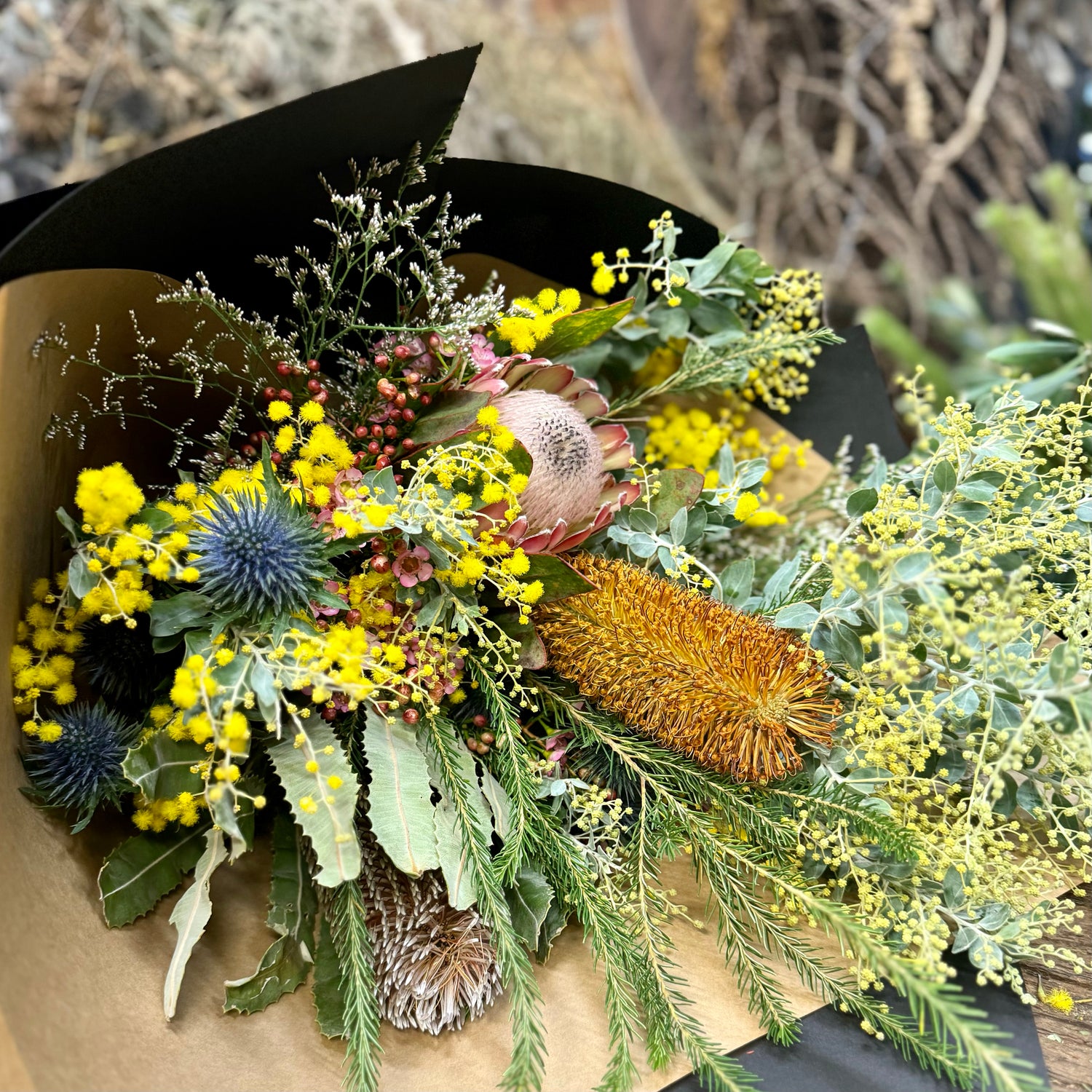 australian natives arranged in a flower bouquet, including proteas, wattle and eucalyptus