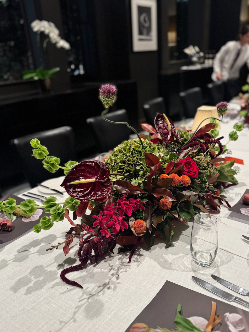 Decorative floral centerpiece on a table with place settings in a restaurant setting.
